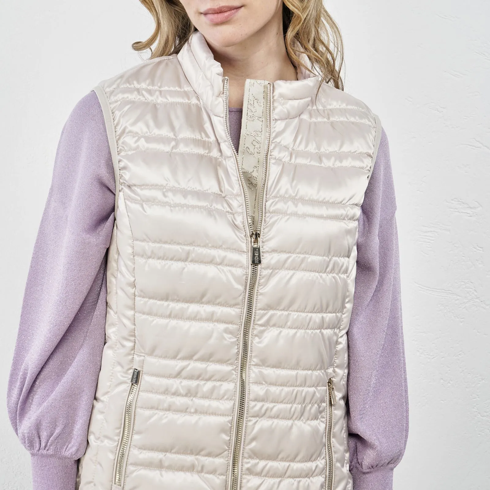 Beige padded vest with zipper and pockets.